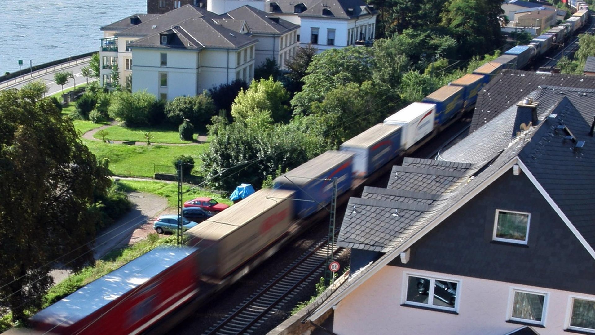 Güterzug auf einer Bahnstrecke unmittelbar neben Wohngebäuden